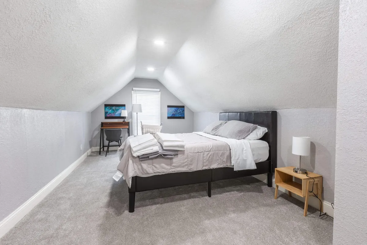 This image features a serene bedroom outfitted with a bed, desk, and lamp, creating a calm retreat that doubles as a workspace. The desk suggests a dedicated spot for productivity or creative brainstorming, complemented by relaxing décor and ample natural light.