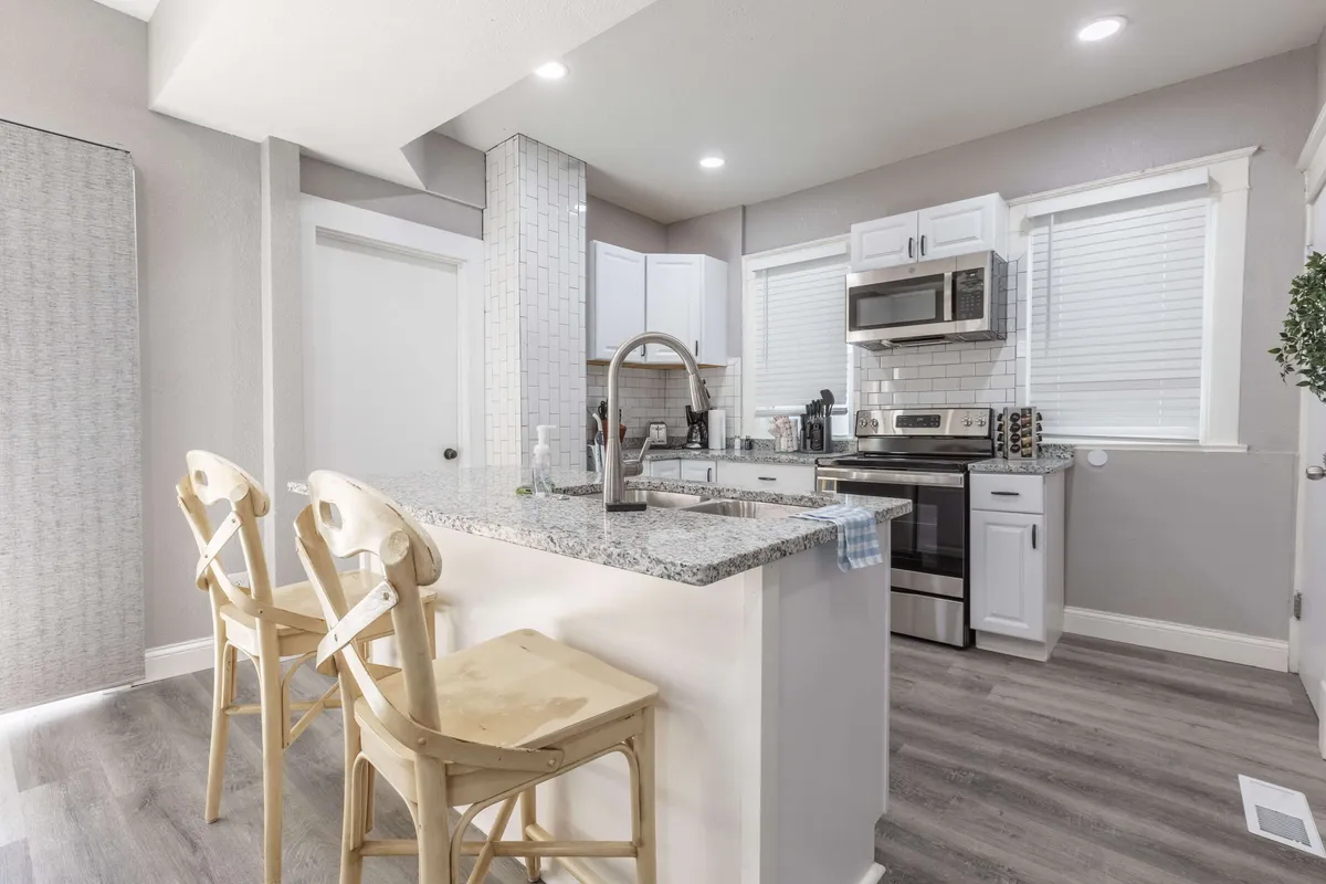 A cozy kitchen with granite countertops, stainless steel appliances, and wooden chairs bathed in morning sunlight. The space is perfect for preparing family meals and socializing after a day of exploring.
